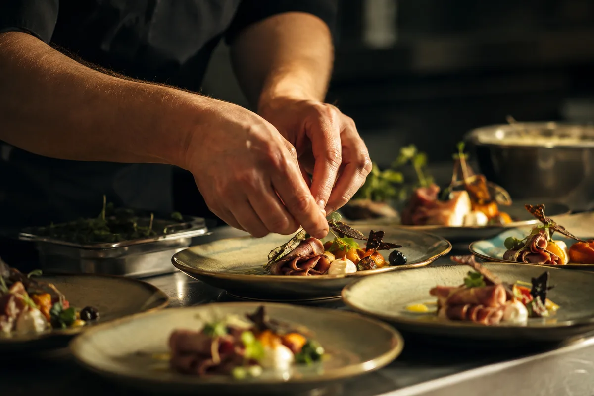 Mains d'un cuisinier dressant des assiettes au passe